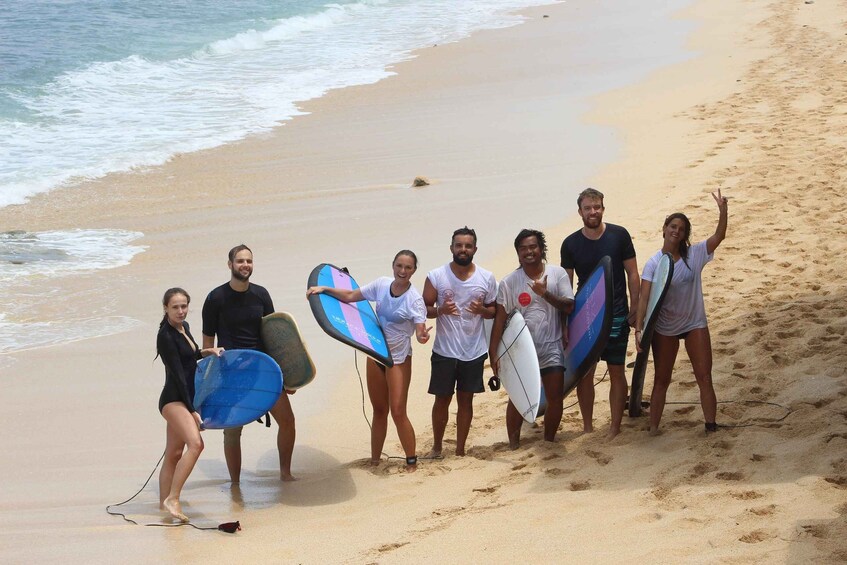 A group of people on a beach holding surfboards. 1