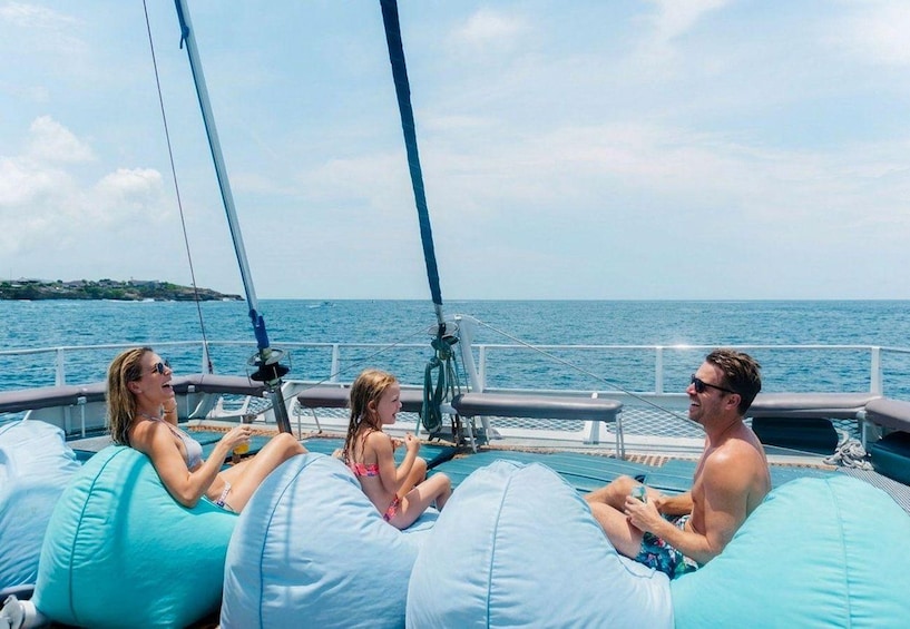 People on a boat, large blue bean bags, and a calm sea. 1