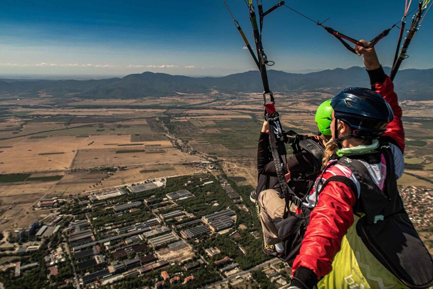 A person paragliding over a landscape with buildings and mountains. 2