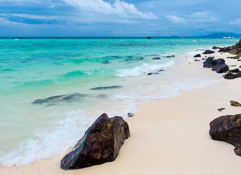 A beach with clear turquoise water, large rocks, and a distant boat. 5
