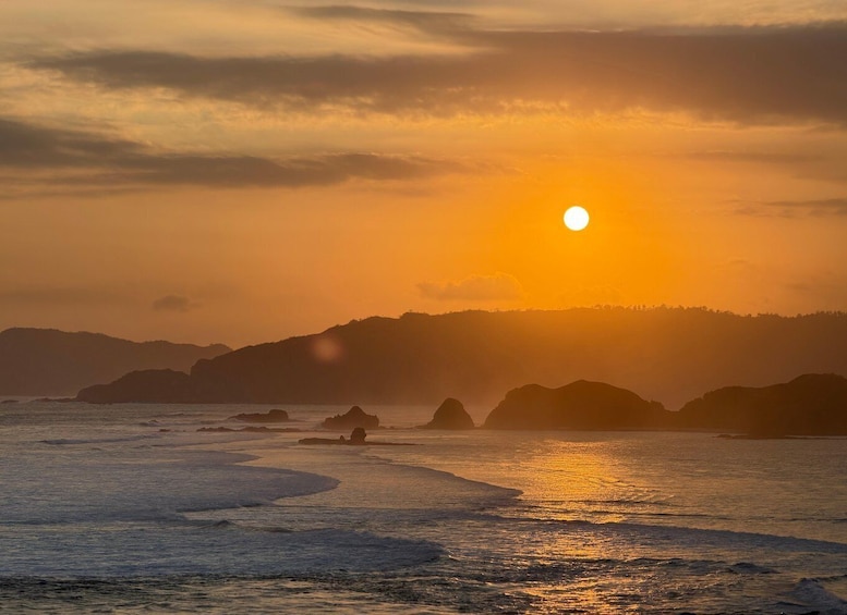 A sunset over a coastal landscape with waves and rocky outcrops. 2