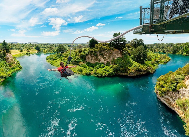 A person bungee jumping from a bridge over a river surrounded by greenery. 5
