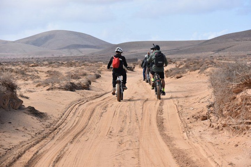 Un grupo de ciclistas en un camino de tierra en un paisaje desértico. 1