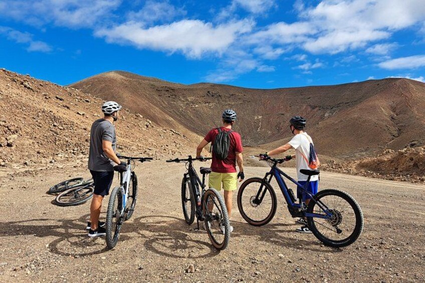 Tres ciclistas en un camino de tierra con montañas al fondo. 4