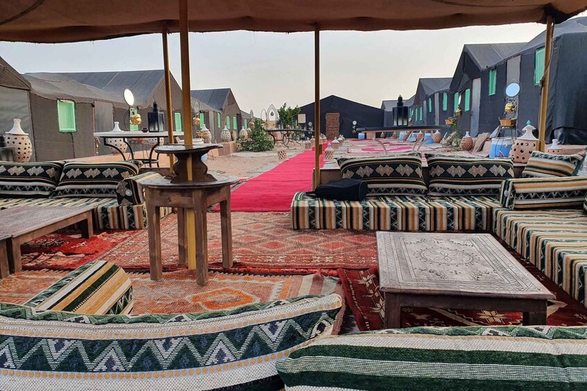 A traditional tented area with patterned cushions and rugs, a red carpet, and a row of buildings in the background. 4