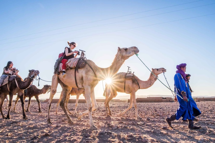 A camel caravan with riders in a desert landscape. 1
