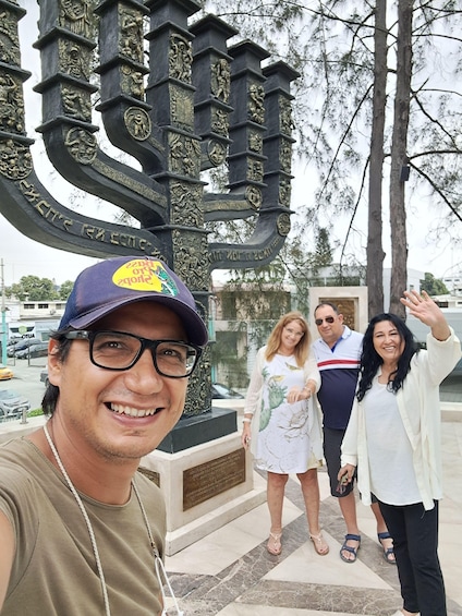 A group of people standing in front of a large, ornate metal gate with inscriptions. 2