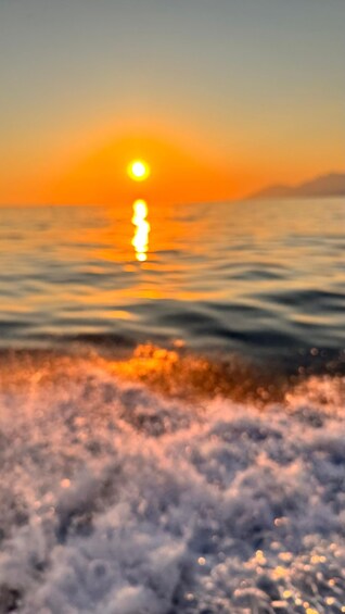 A sunset over a body of water with waves in the foreground. 4
