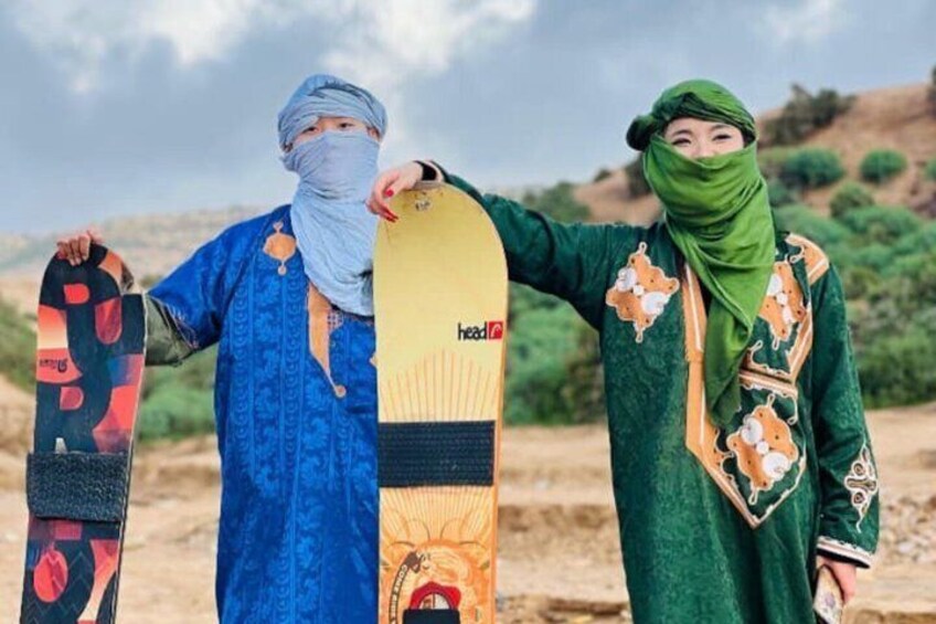 Deux personnes, chacune tenant une planche de snowboard au design distinct, se tiennent debout dans un paysage naturel. 2