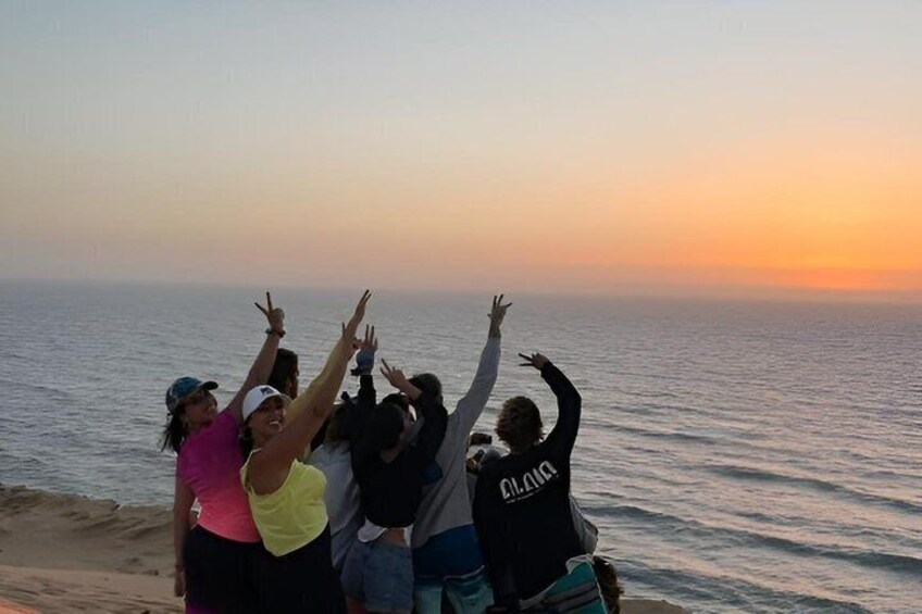 Un groupe de personnes sur une plage au coucher du soleil. 1