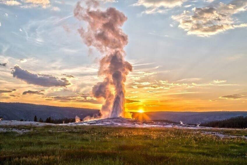 A geyser erupting with steam against a sunset sky. 1