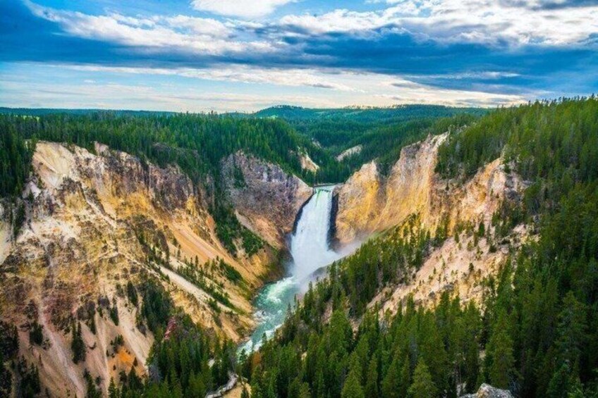 A canyon with a waterfall, surrounded by dense forest. 2