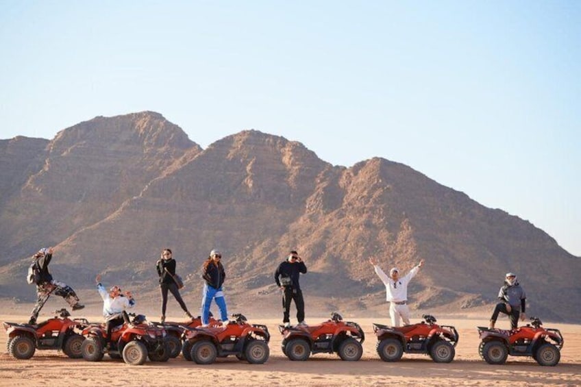 Een groep mensen op quadbikes in een woestijn, met bergen op de achtergrond. 4