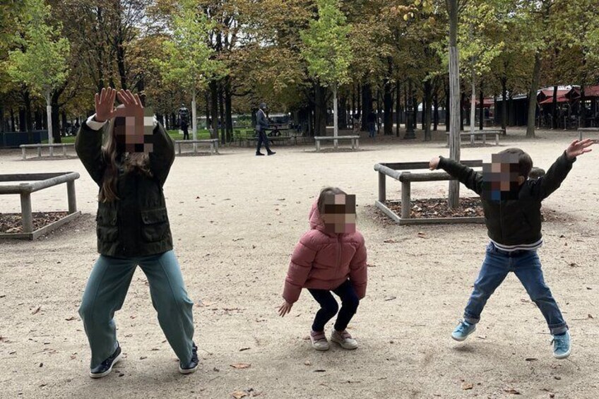Three children playing in a park with trees and benches. 3