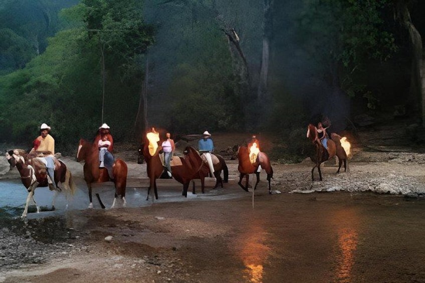 A group of people riding horses along a riverbank at dusk. 3