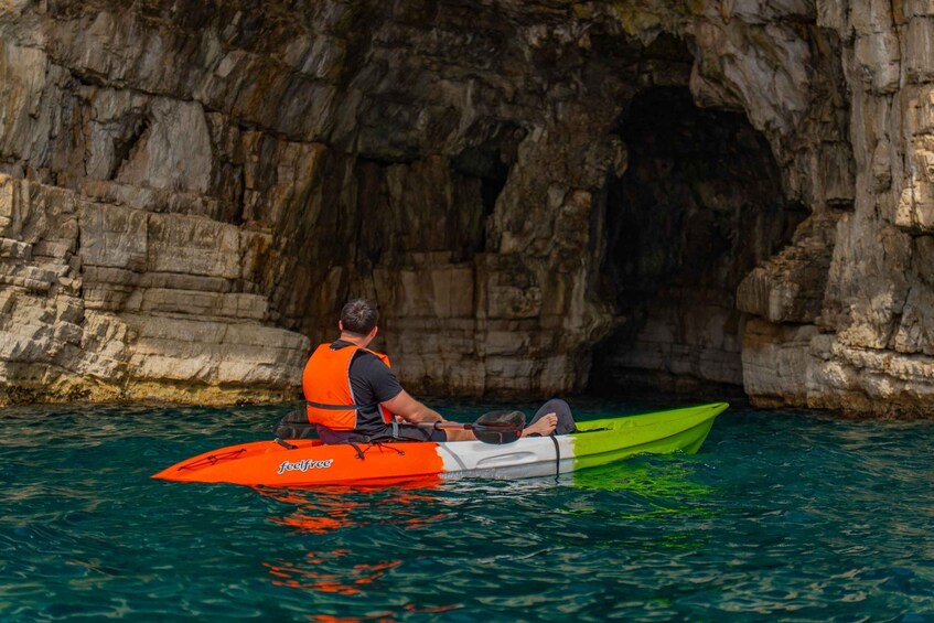 Two people kayaking in a cave with a rocky backdrop. 2