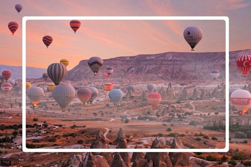 Un paysage parsemé de nombreux ballons à air chaud, avec un terrain rocailleux et une chaîne de montagnes en arrière-plan. 1