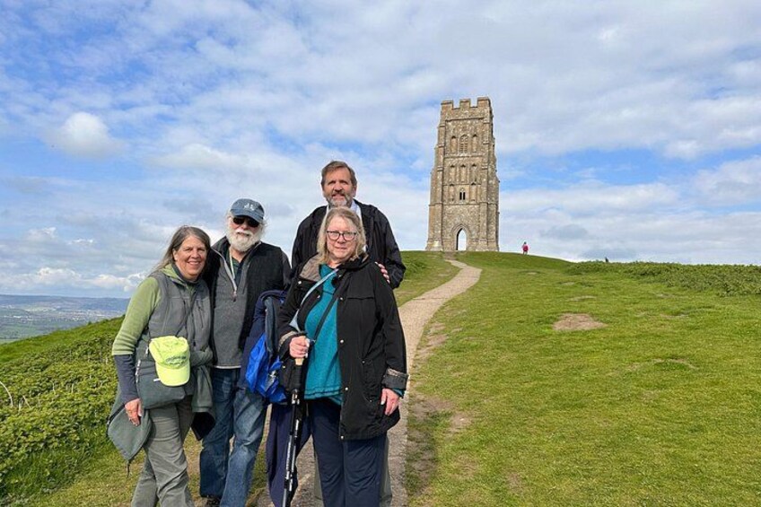 A group of people standing on a grassy hill with a tower in the background. 2