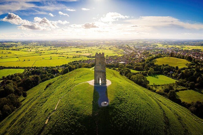 A tower on a grassy hill with a village in the background. 2