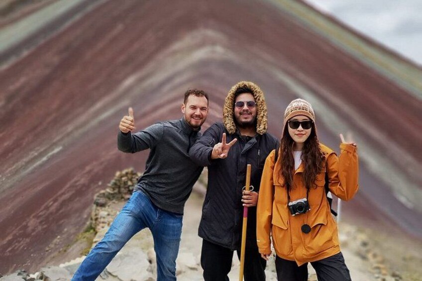 Three people posing in front of a striped rock formation. 1