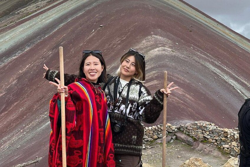 Two people standing in front of a large rock formation with a wooden structure. 5