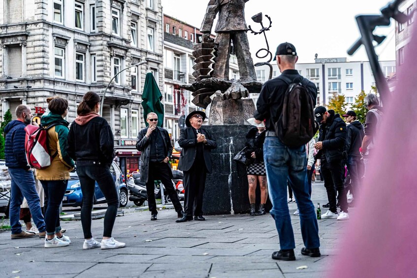 A group of people standing around a sculpture in an urban setting. 3