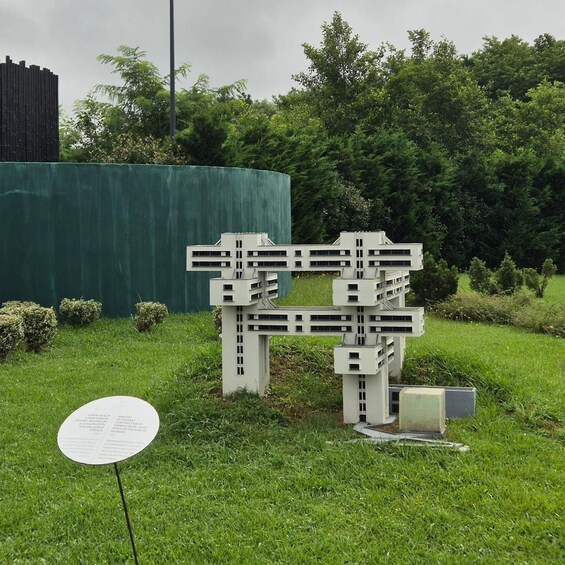 A modern sculpture in a grassy area with a sign and trees in the background. 2