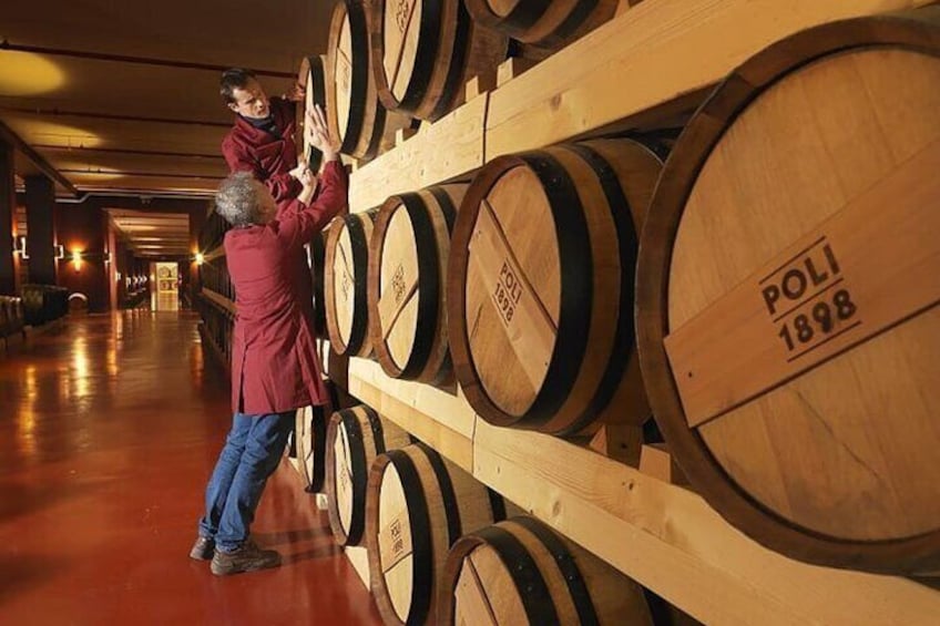 Una persona revisando barriles de madera en un almacén. 5