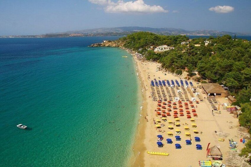 Una playa con agua turquesa cristalina, hileras de sombrillas coloridas y algunas cabañas de playa. 3