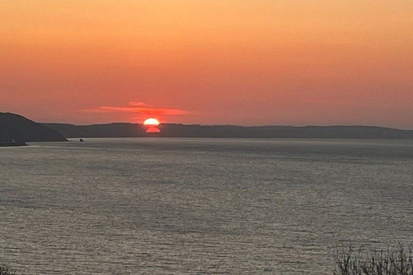 Solnedgang over et roligt hav med en fjerntliggende kystlinje. 2