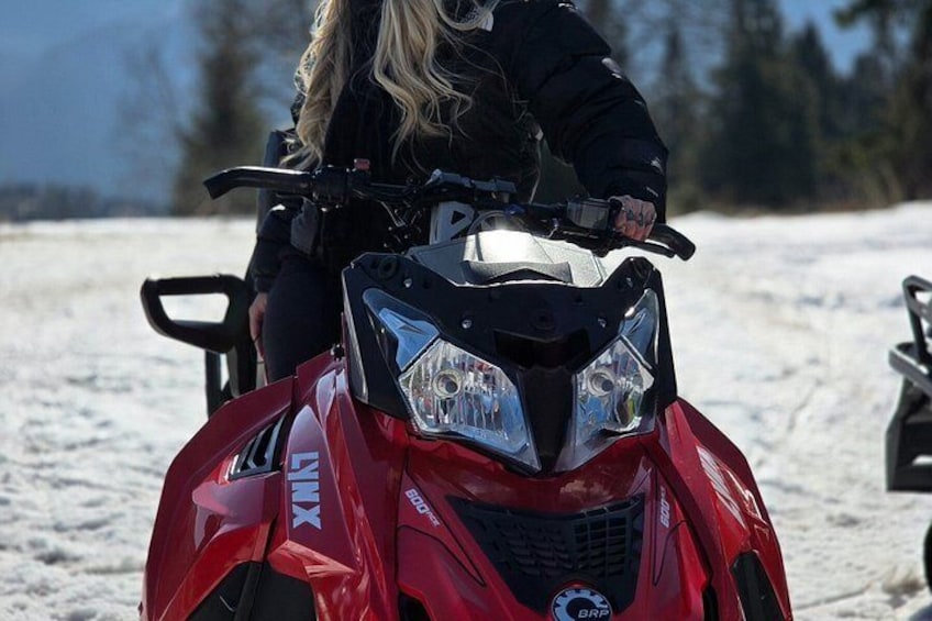 A red snowmobile with a person sitting on it. 1