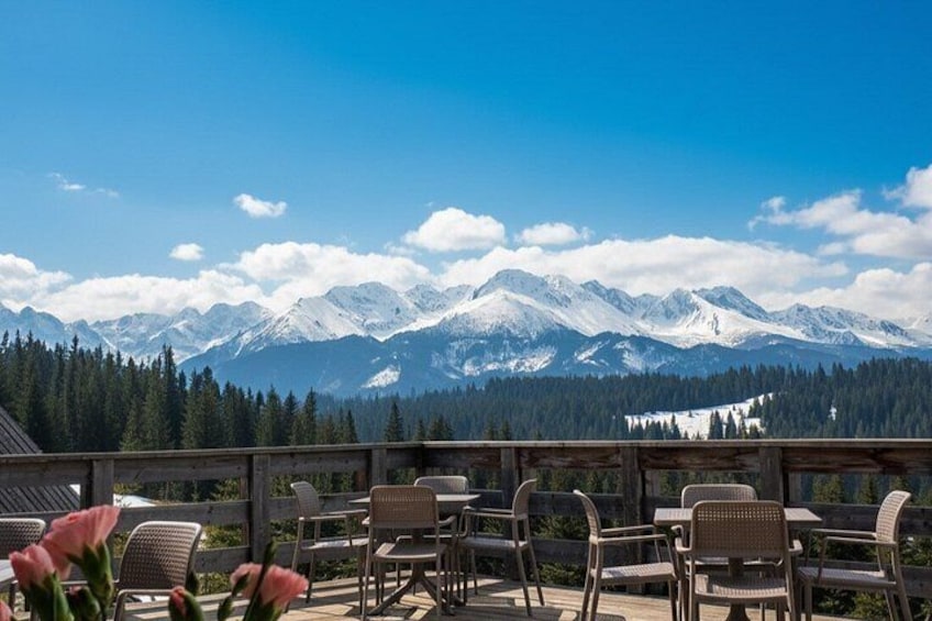 Eine Terrasse mit Stühlen und Blick auf schneebedeckte Berge. 2