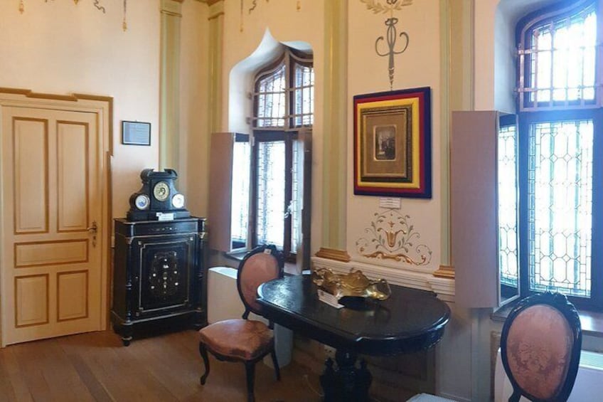 A dining room with a wooden table, chairs, a clock, and a window with decorative iron bars. 3
