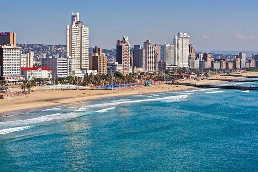 A coastal cityscape with a beach, high-rise buildings, and a clear blue sky. 3