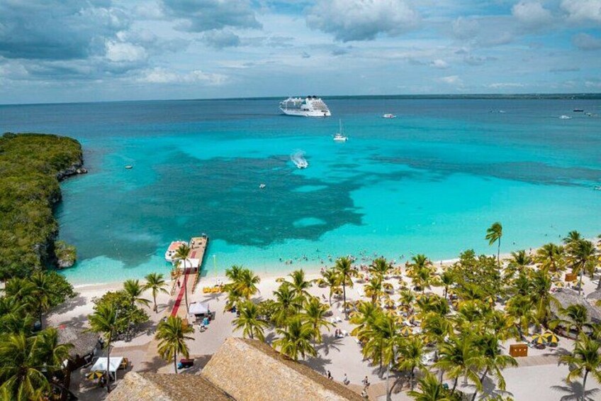 A beach with palm trees, a cruise ship, and clear turquoise waters. 5