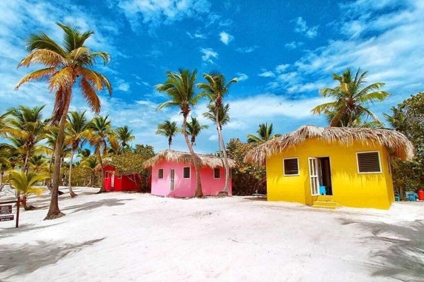 A beach with colorful huts, palm trees, and a clear blue sky. 4