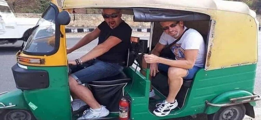 Two people in a green and yellow auto-rickshaw. 5