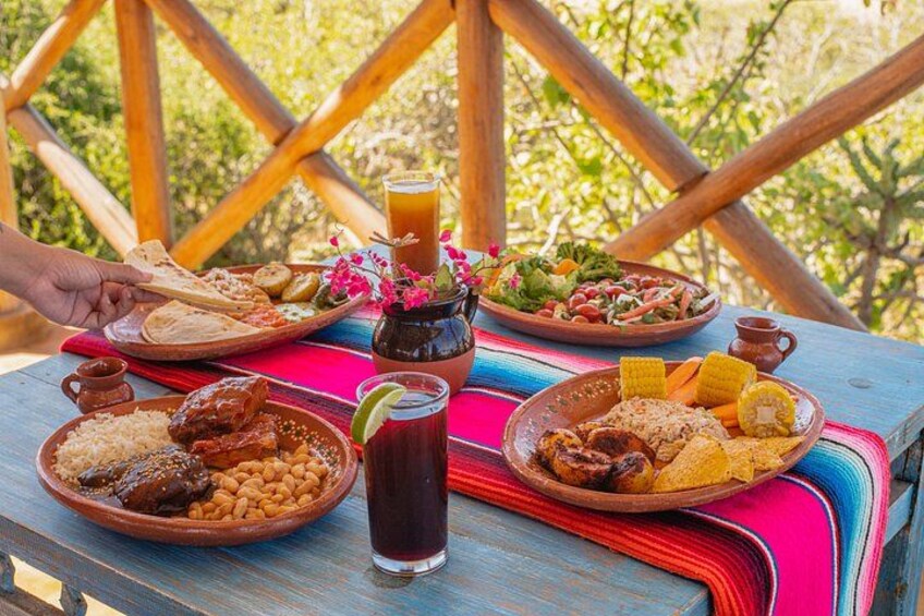 A table with various dishes, drinks, and a colorful tablecloth. 4