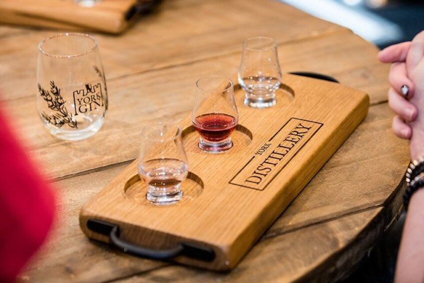 Un plateau en bois avec trois verres, dont l’un est rempli d’un liquide rouge, et un verre orné de motifs floraux. 4