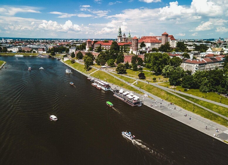 A river with boats, a castle, and a park with people. 2