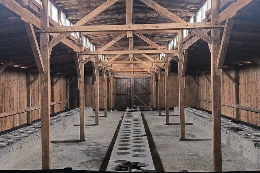 An interior with wooden beams, a central walkway, and a concrete floor. 2