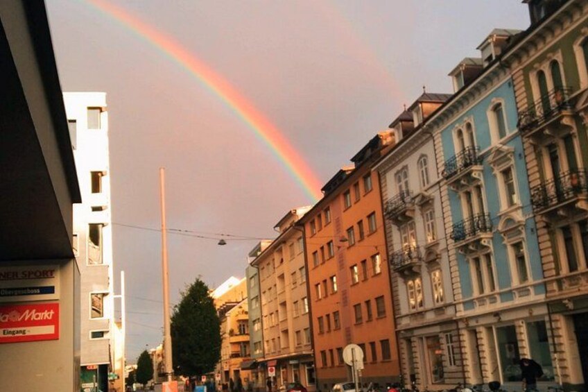 A rainbow over a city street with buildings and a sign for 'NellSport'. 3