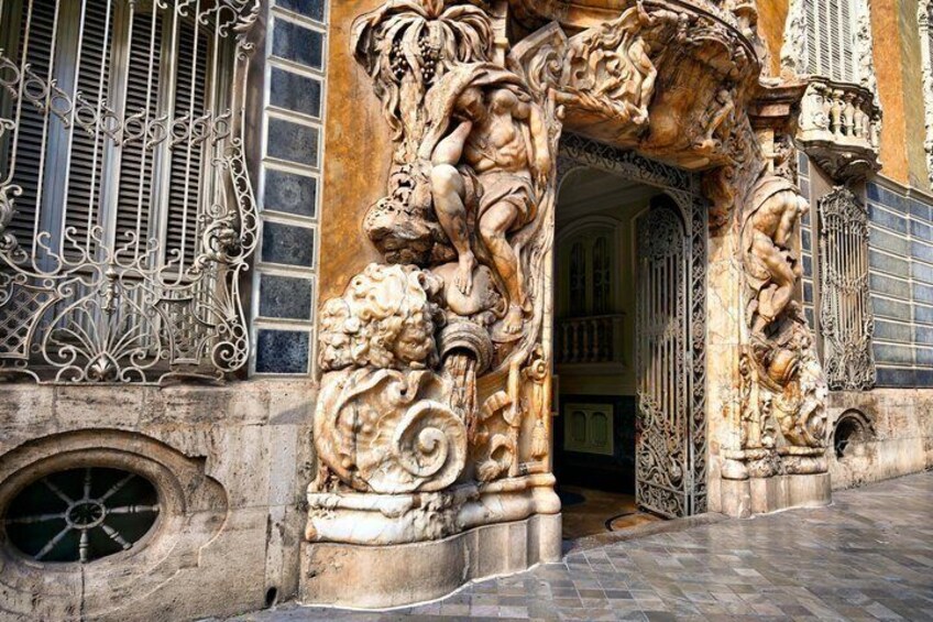 An ornate architectural doorway with intricate carvings and a metal gate. 2