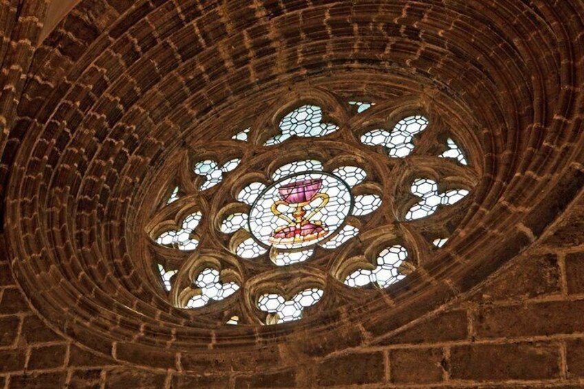 A cathedral's ribbed vault ceiling with a central stained glass window. 3