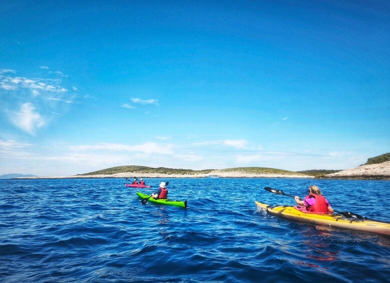 People kayaking on a calm sea with clear skies and distant land. 1