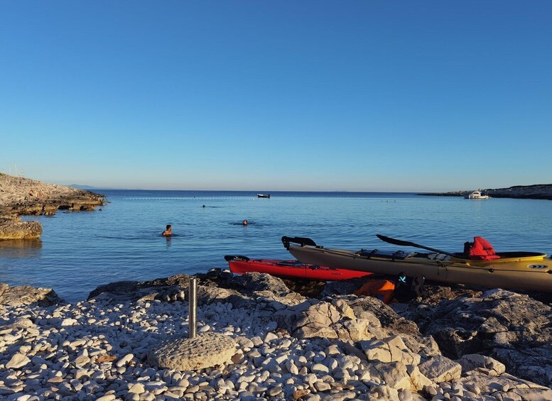 A rocky shoreline with kayaks and a boat in the water. 3