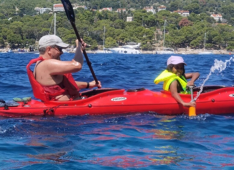 Two people in a red inflatable kayak on a body of water with a coastal landscape in the background. 5