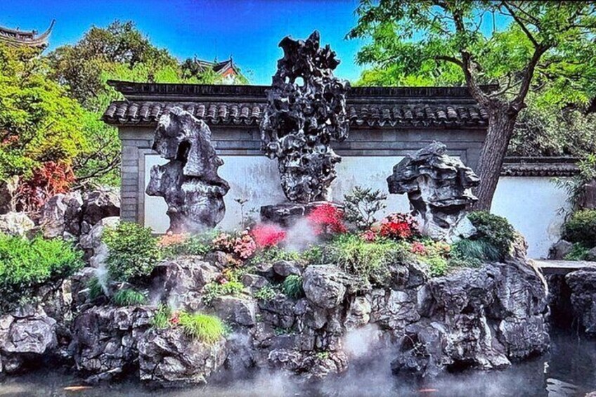 Un jardin de rocaille chinois traditionnel, agrémenté de statues, d’une végétation luxuriante et d’un ciel d’un bleu éclatant. 1