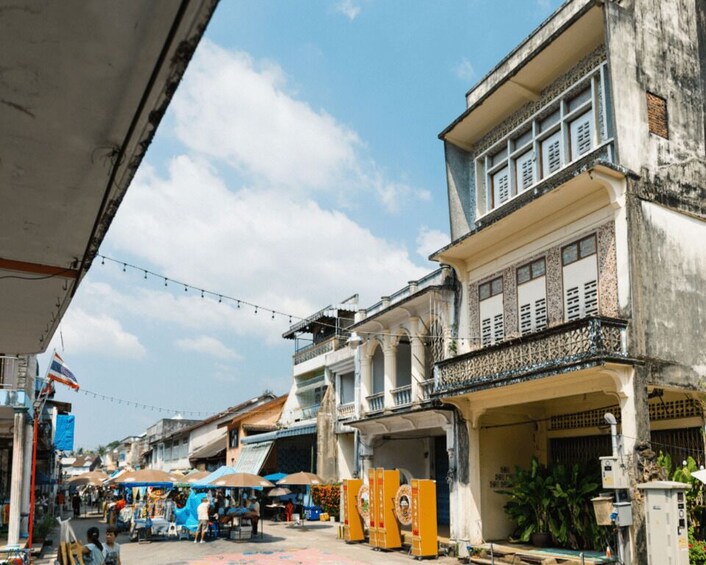 A bustling street with market stalls and a mix of residential and commercial buildings. 1