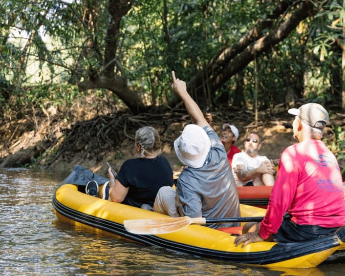 People in a yellow raft on a river surrounded by trees. 4